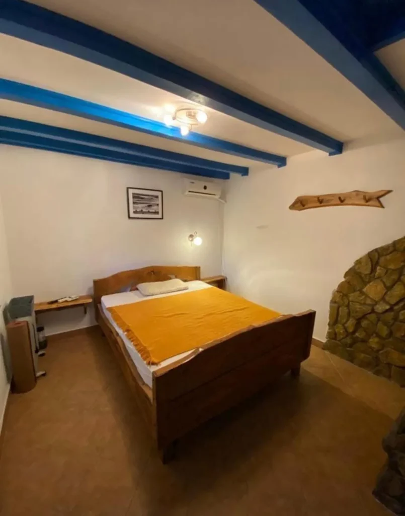 Dormitor rustic cu grinzi albastre și pat dublu